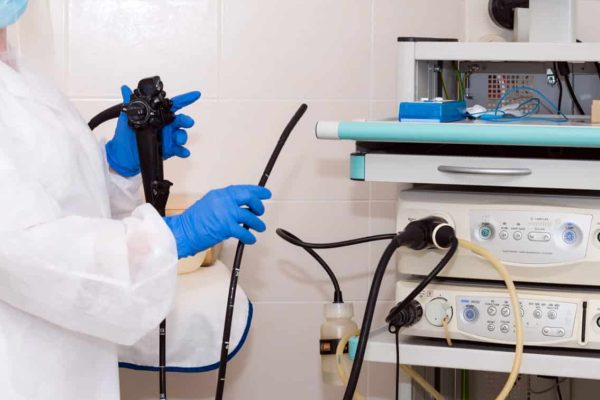 Doctor gastroenterologist in protective clothing holding endoscope before gastroscopy